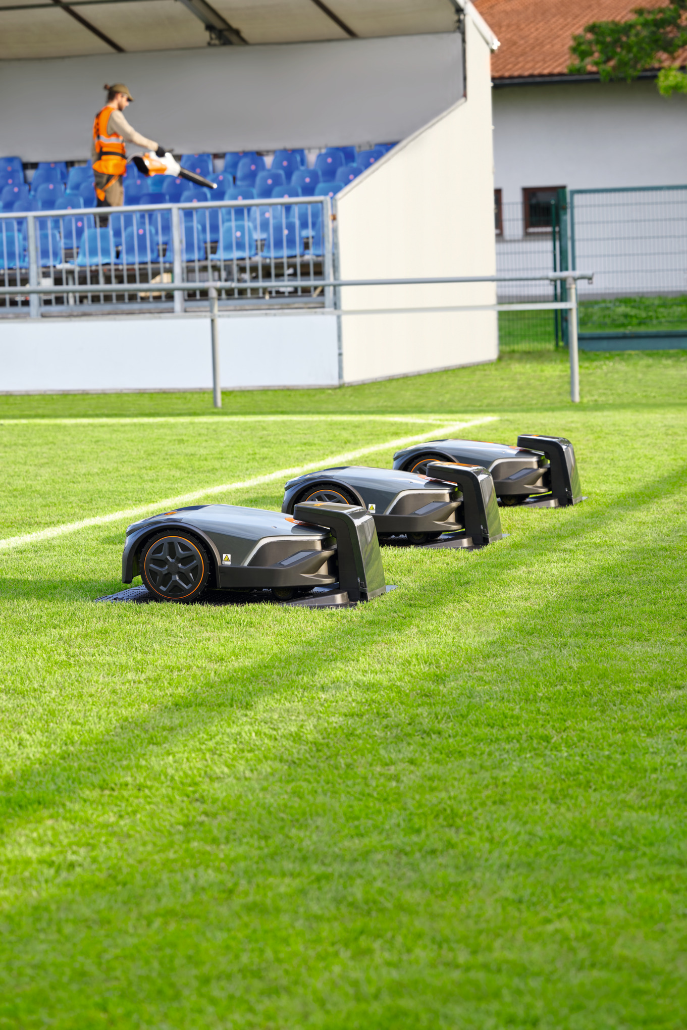 Three STIHL iMOW® PRO robot mowers on a football pitch